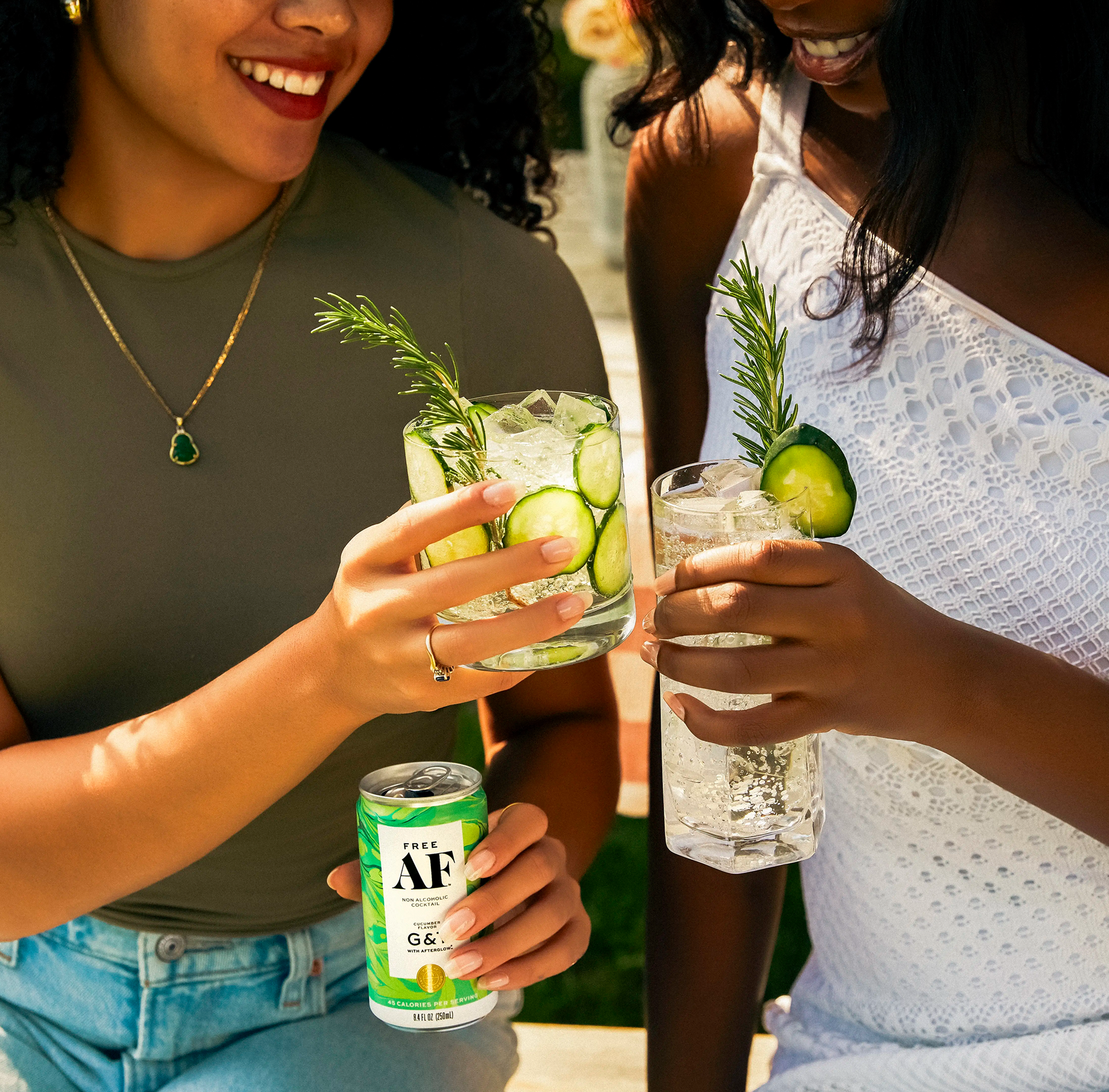 Two people holding glasses with orange drinks near cacti.